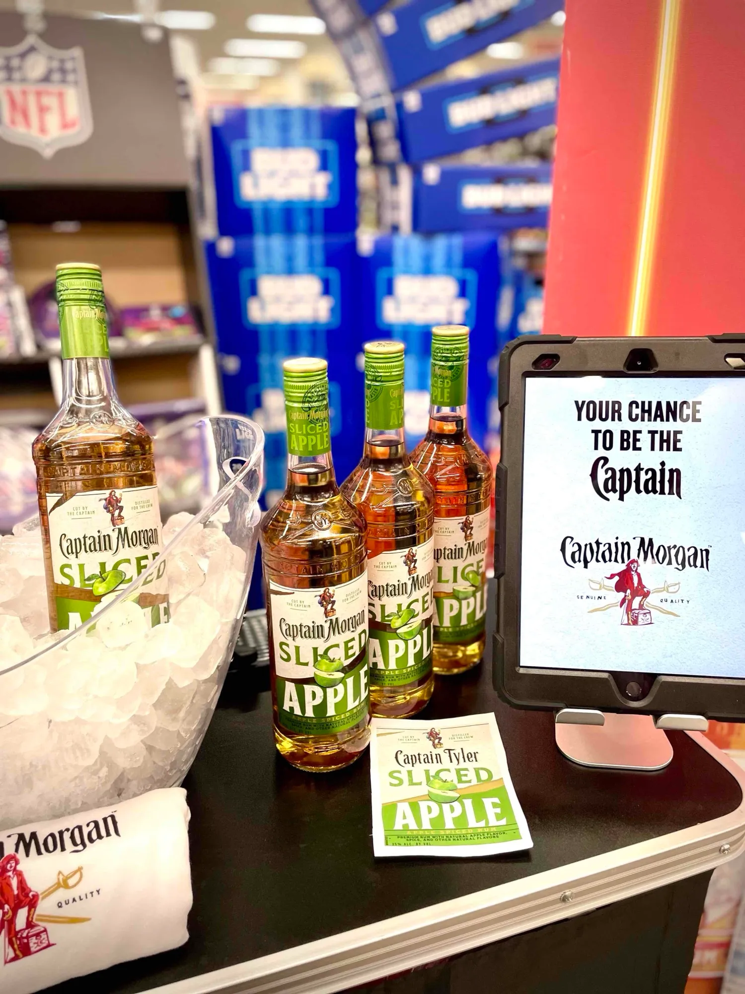 A Captain Morgan Sliced Apple stand in a store, with bottles, a personalised label and the app on an iPad: Your chance to be the Captain
